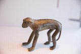 Vintage handmade monkey figurine with an aged patina, shown in a full-body side profile.