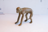 The vintage monkey figurine's unique profile, highlighting its carved spine and weathered surface.