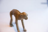 Aged patina and handmade texture on the face of the vintage African monkey sculpture.