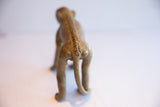 Rear view of the vintage monkey figurine showing its carved spine and long tail.