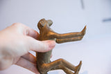 Vintage African monkey figurine held to show its size and textured patina.