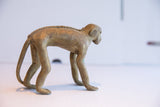 Profile of a vintage monkey figurine showing its aged patina and braided spine detail.