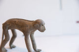 Profile view of the vintage monkey figurine's head, showing its simple features and aged patina.