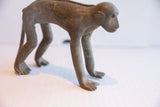 Angled profile of a vintage monkey figurine highlighting its handmade form and aged texture.