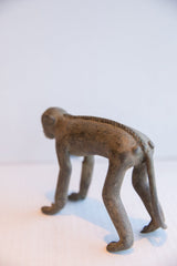 Rear view of a vintage monkey figurine with a textured, ridged spine.