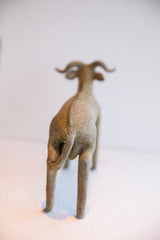 Vintage African ram sculpture viewed from behind, showing its textured spine and tail.