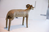 The vintage ram sculpture's curved horns and slender body seen from a rear angle.