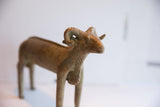 Textured, curled horns and aged patina on the head of a vintage ram sculpture.