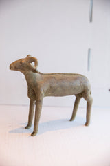Profile view of a vintage African ram sculpture, showing its aged patina and handmade texture.