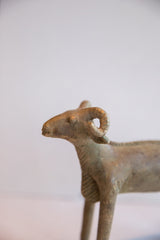 Profile view of the vintage ram sculpture's head, detailing its curved horn and aged patina.