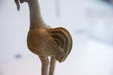 Intricate layered wing details and ribbed texture of the vintage African rooster sculpture.