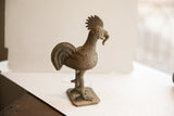 Profile view of a vintage African rooster sculpture highlighting its handmade textures.
