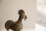 Profile detail of the vintage rooster sculpture highlighting its comb and textured, ringed neck.