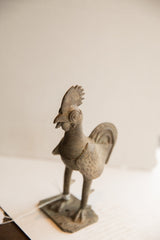 Textured body and ribbed neck of vintage African rooster sculpture with aged patina.