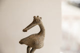 Detailed profile of the African bird sculpture showing its crowned head and handmade texture.