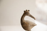 Close-up profile of a vintage African bird sculpture's head detailing its crown and spiral eye.