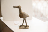 Vintage African bird sculpture in profile showing its textured body and aged patina.