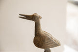 Side view of the vintage bird sculpture's head showing its handmade texture and carved eye.