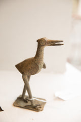 Profile view of a vintage African bird sculpture highlighting its textured body and stance.
