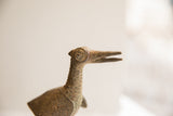 Profile view of the vintage bird sculpture's head, showing its carved circular eye.