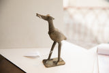 Profile view of a vintage African bird sculpture highlighting its handmade texture.