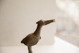 Angled close-up of the vintage bird sculpture's head showing its circular eye and stippled neck.