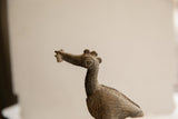 The textured, handcrafted head of a vintage African bird sculpture holding a fish.