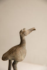 Aged patina and carved spiral eye on the head of a handmade vintage African bird sculpture.