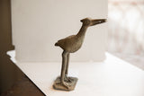 Profile view of a vintage African bird sculpture showing its spiral eye and textured body.