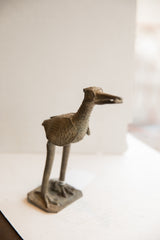Profile of a vintage African bird sculpture with a fish, showing its aged, textured patina.