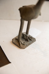 Detail view of the vintage African sculpture's textured feet and etched square base.