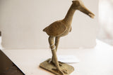 Rear view of the vintage African bird sculpture, showing its weathered texture and long legs.