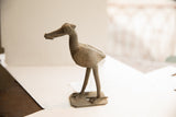 Vintage African bird sculpture with a fish, viewed from the side to show texture.
