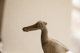Detailed profile of the vintage African bird sculpture's head, highlighting its circular eye and textured finish.
