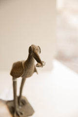 Head detail of a vintage bird sculpture with spiral eyes holding a fish in its beak.