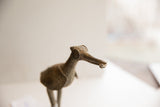 Stylized eye and textured beak of a vintage African bird sculpture holding a fish.