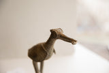 Profile view of the vintage bird sculpture's head, highlighting its circular eye and aged texture.