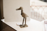 African bird sculpture with textured head, long beak, and circular eye detail.