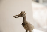 Close-up of vintage African bird sculpture's textured head, long beak, and patterned wing.