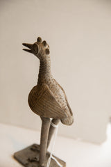 Close-up of vintage African bird sculpture's textured legs and base with white tag.