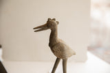 Profile view of a vintage African bird sculpture showing its handmade textured surface and spiral eye.
