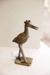 Vintage African bird sculpture in profile, highlighting its handmade texture and form.