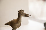 Detailed profile of the vintage bird sculpture's head, showing a spiral eye and textured patina.