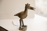 Vintage African bird sculpture holding a fish, showing its textured profile.