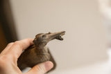Close-up of the vintage bird sculpture's textured head holding a fish in its beak.