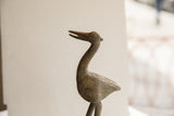 Stylized head and curved neck of a vintage African bird sculpture showing a spiral eye.
