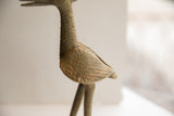 Detailed side view of the vintage bird sculpture's textured metal and incised wing.