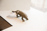 Angled view of the vintage pangolin sculpture showing its textured, scaled body.