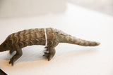 The curved body and hand-carved scale texture of a vintage pangolin sculpture.