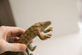 A hand holding the vintage pangolin sculpture, showing its textured scales.